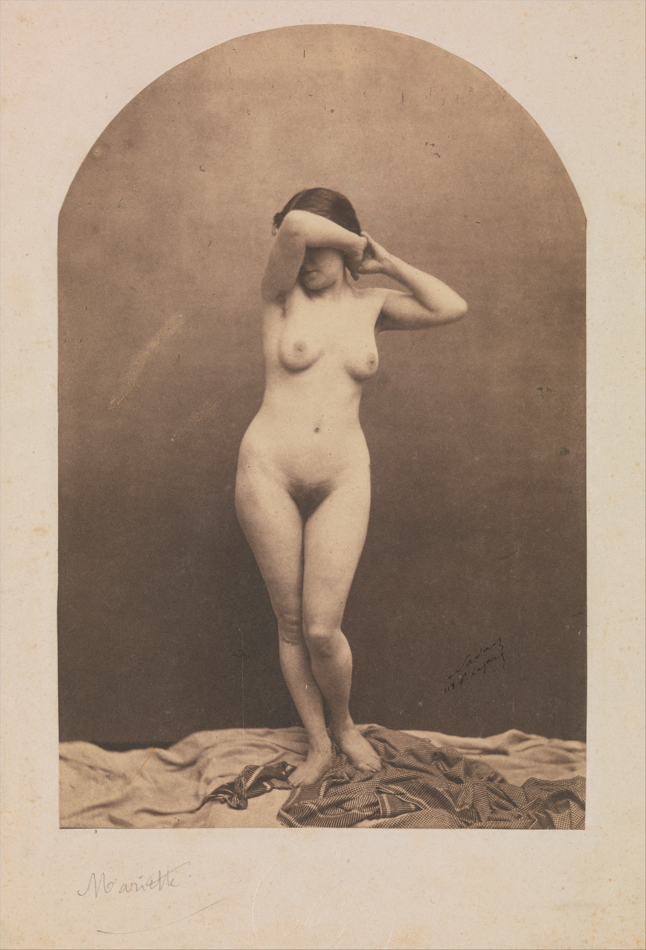 Nadar 的站立女性裸体照片,人物在摄影画室的中性背景前站立。